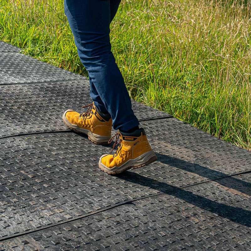 Person walking on non-slip temporary access boards, used on an incline in a field