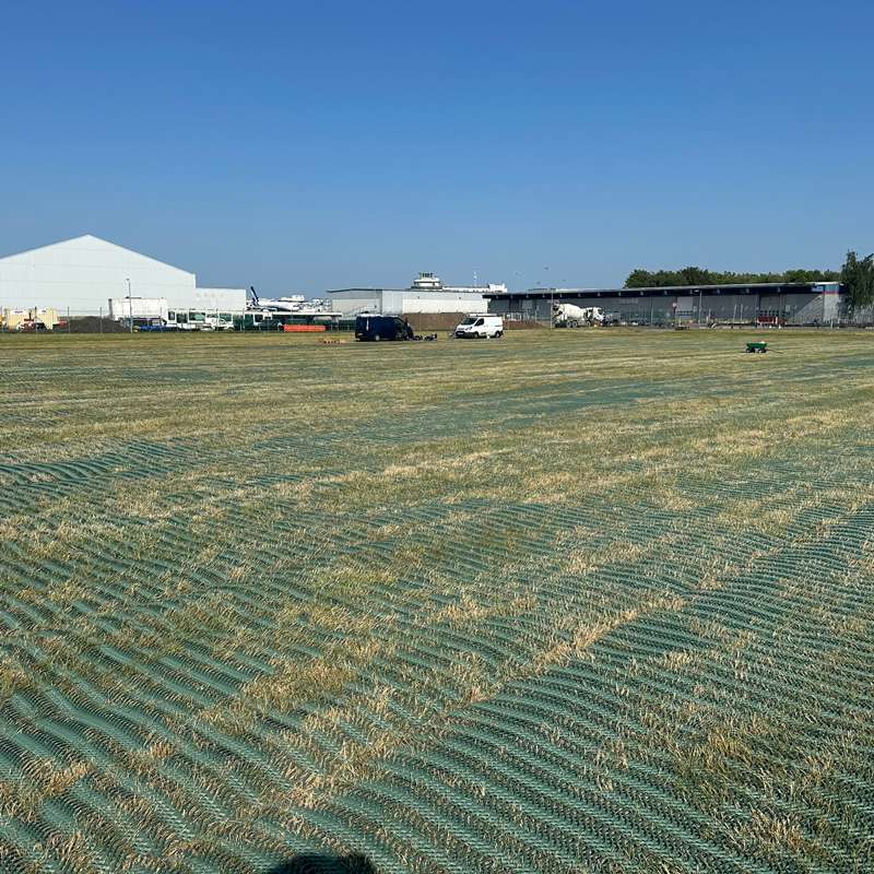Wide angle showing large section of reinforced grass laid for use as overflow parking near the Airport.
