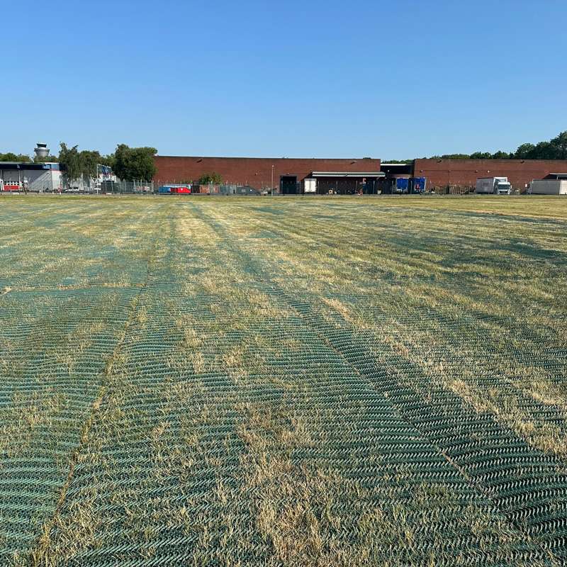 Central perspective view of grass mesh car park stretching across the field toward NCP infrastructure.
