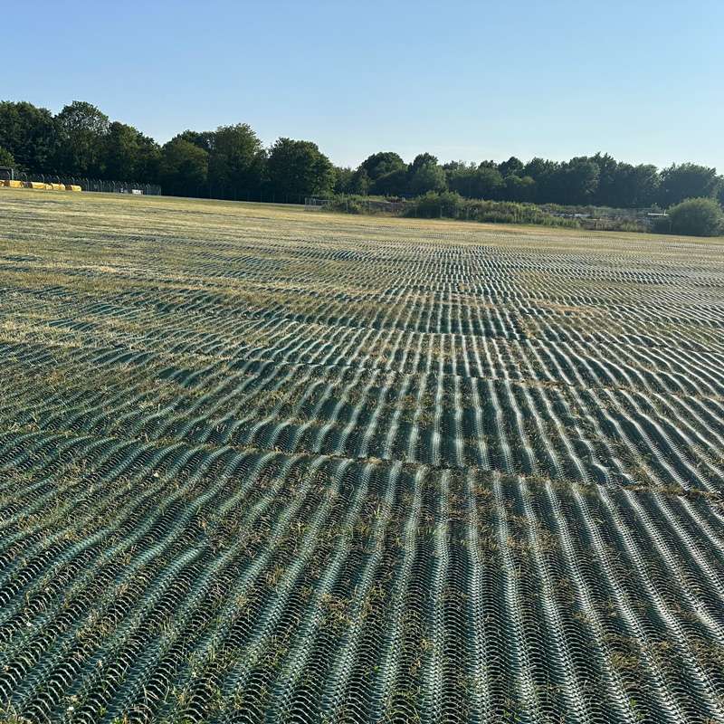 Detailed look at mesh texture over grass with the sun casting shadow lines across the field.