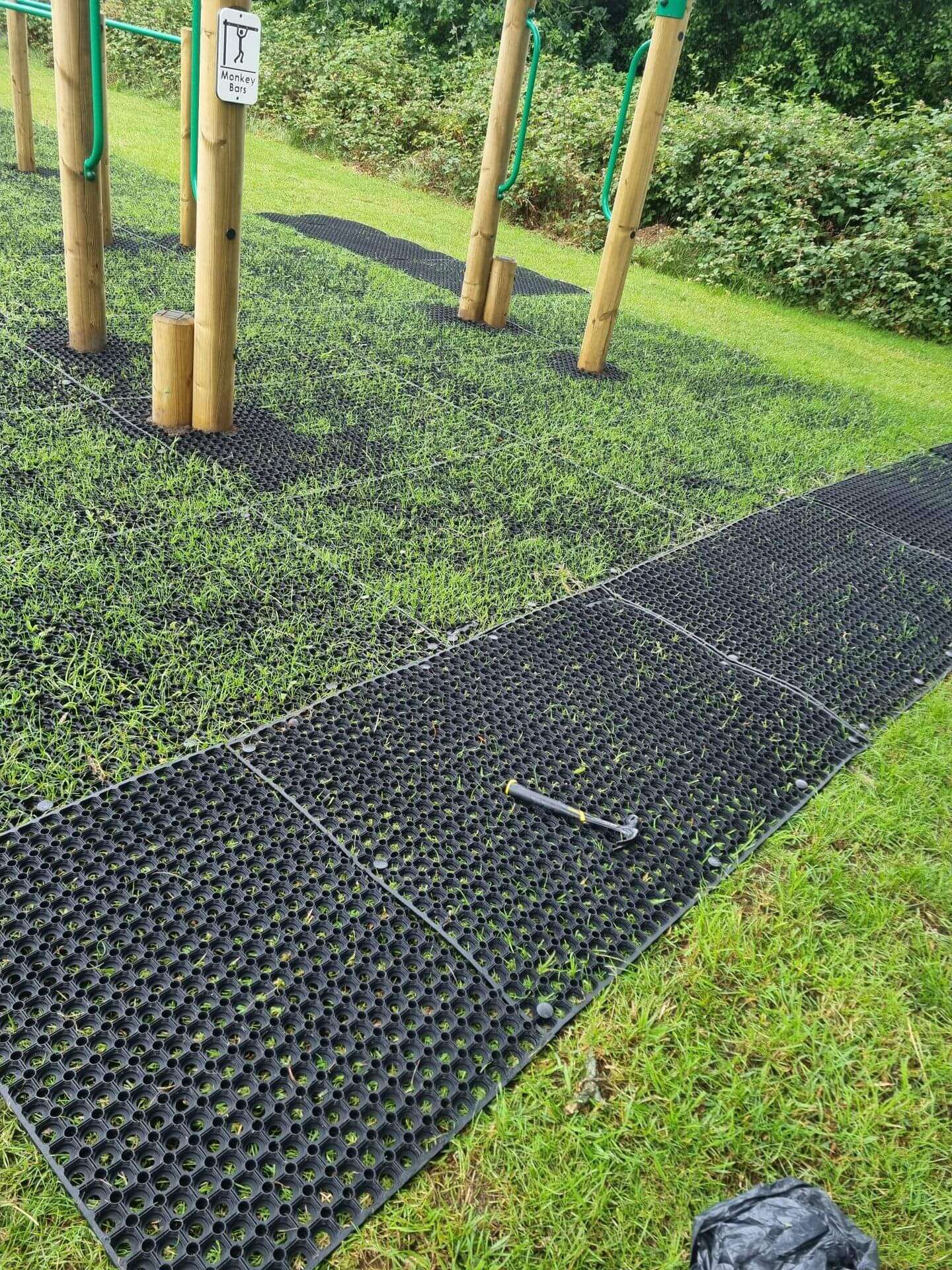 Rubber grass mats installed beneath monkey bars in a public park