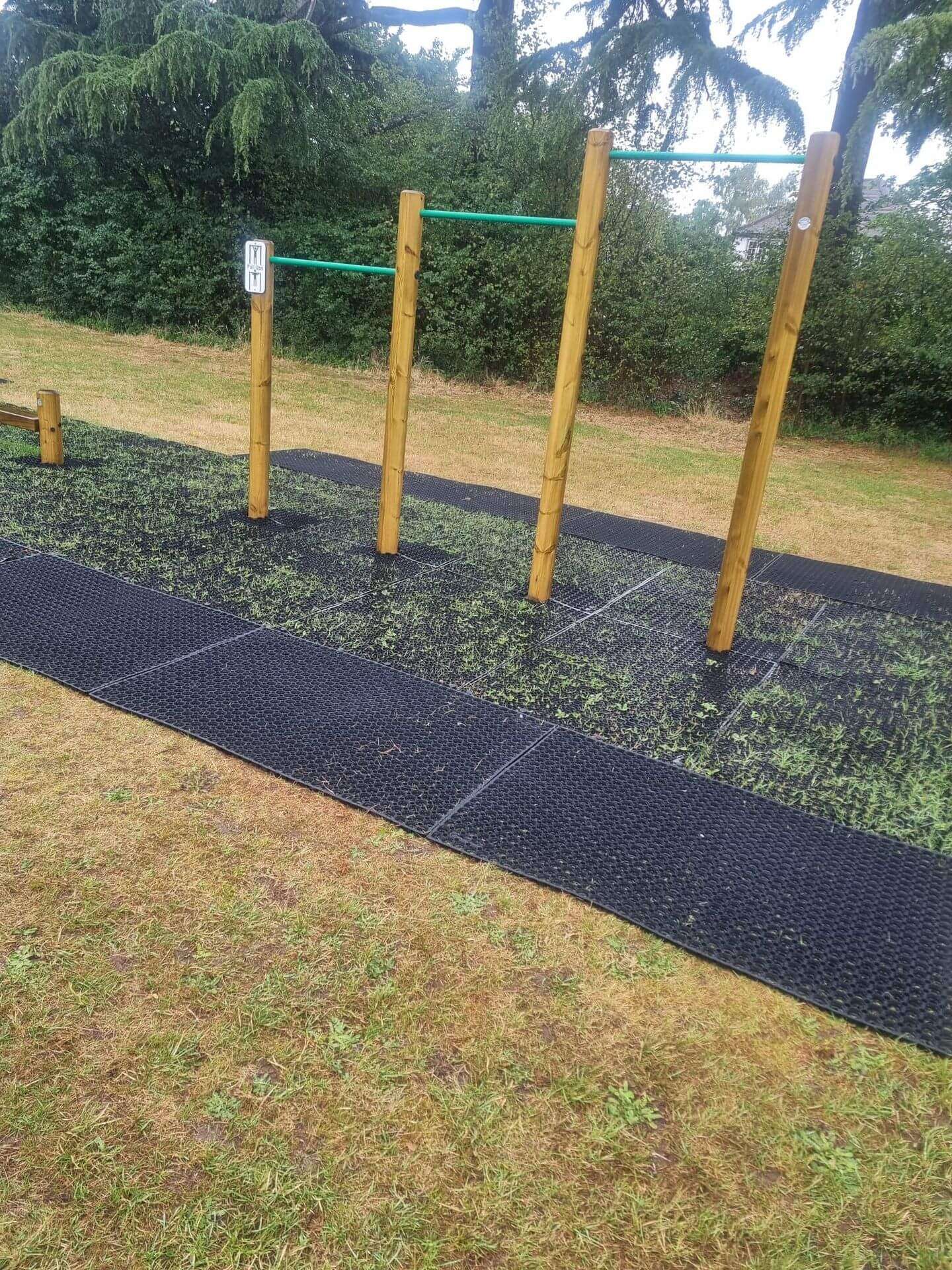 Rubber playground safety mats installed around outdoor trim trail bars