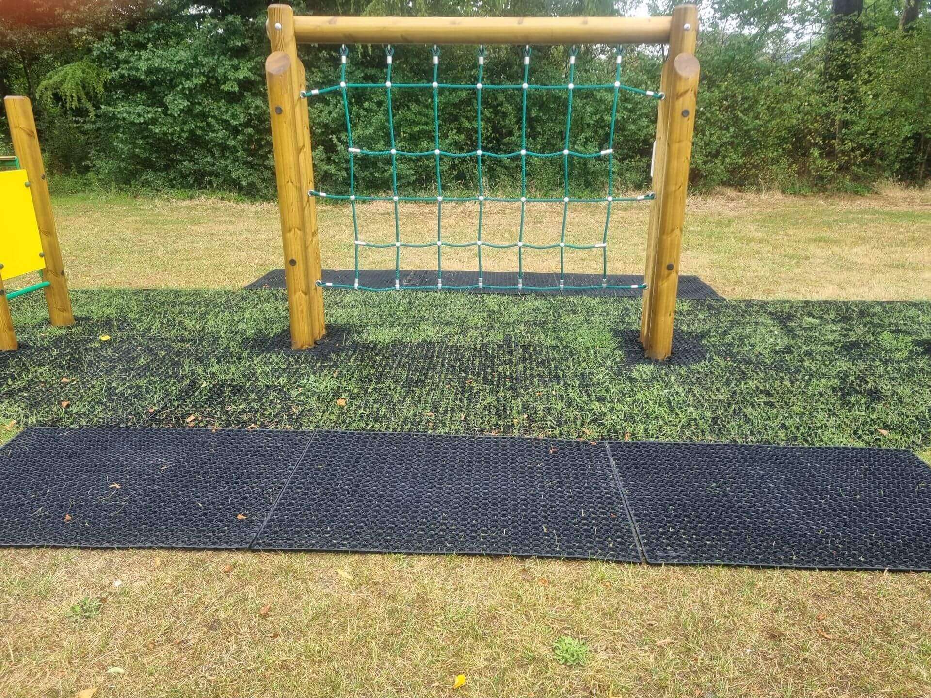 Playground safety grass mats beneath rope climbing equipment